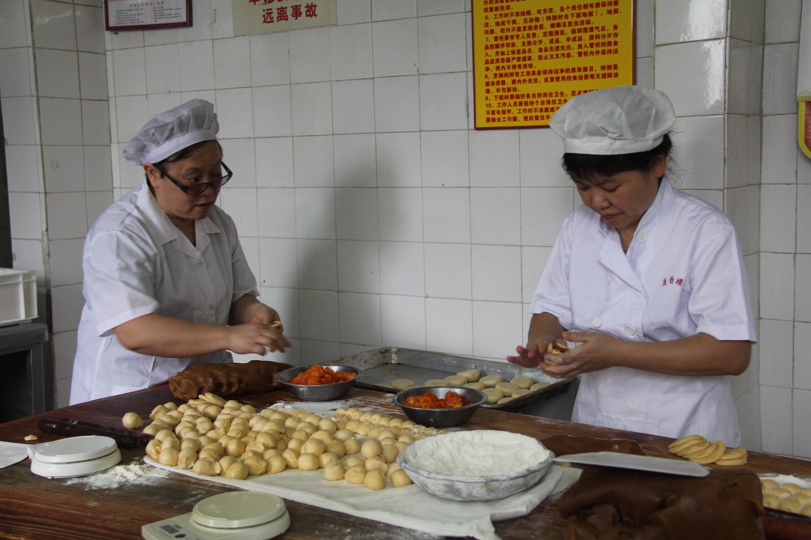 霍一群、刘朝霞师傅把制作好的莲蓉馅料包入龙凤饼饼皮中（2013年9月5日摄于广州第十甫路莲香楼厂房）.jpg